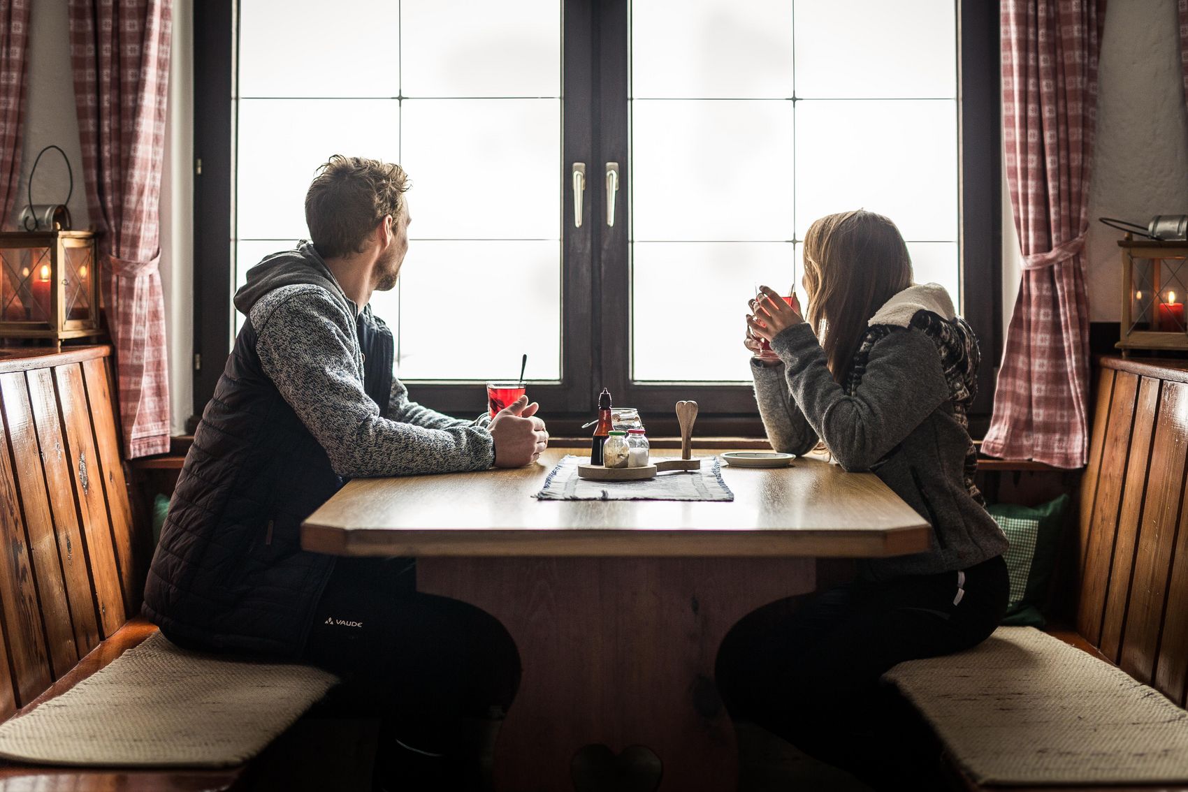 Mann und Frau am Tisch in Restaurant blicken aus dem Fenster in Tirol
