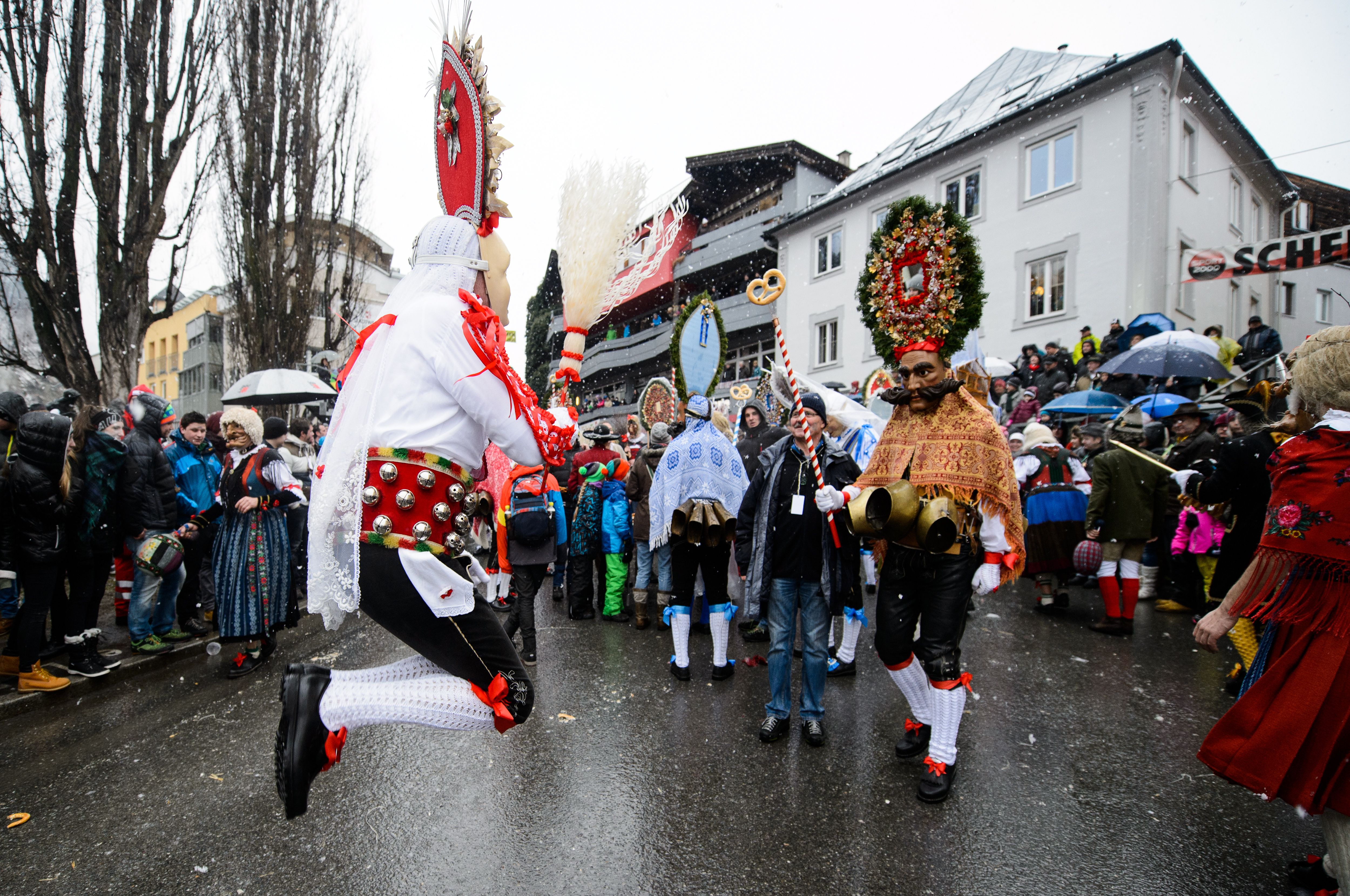 Kostümierter Maskenmensch hüpft auf Fasnacht, viele Menschen im Hintergrund