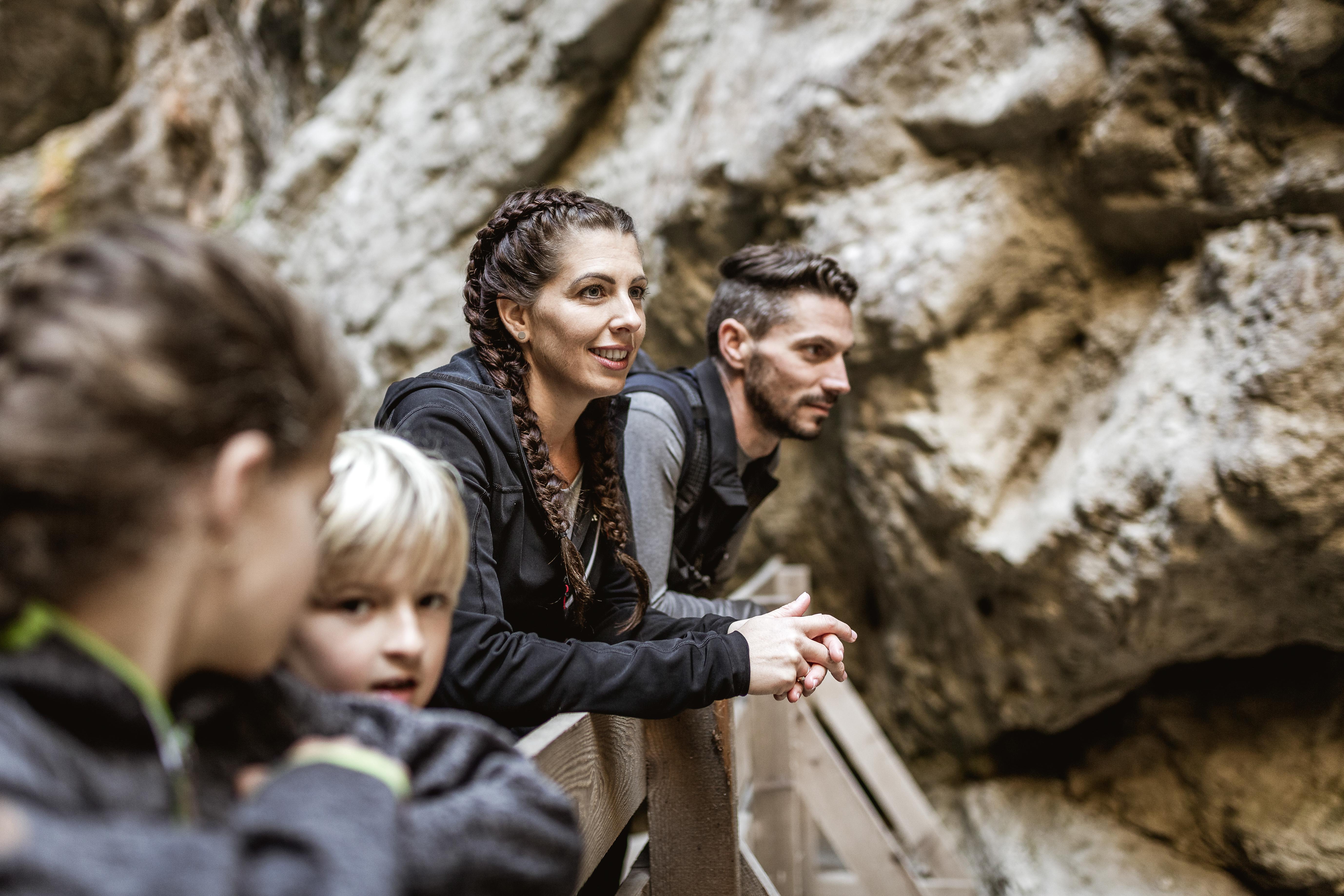 Familie mit Eltern und Kinder stehen auf Brücke in einer Schlucht mit Mutter im Fokus