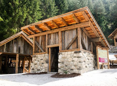 Ein Gebäude aus Ziegelsteinen mit einem Holzdach und Bäumen im Hintergrund.