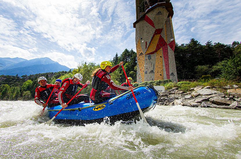 Auf dem Foto ist ein Rafting-Boot mit mehreren Personen auf einem Gewässer zu sehen.
