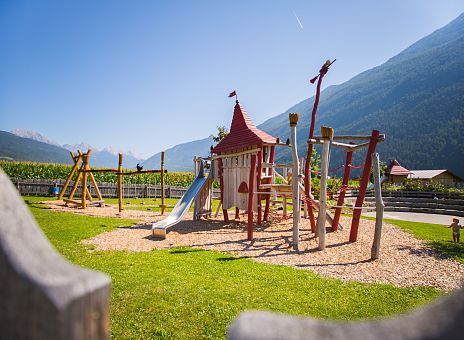 Auf dem Bild ist ein Klettergerüst aus Holz auf einem Spielplatz im Freien zu sehen.